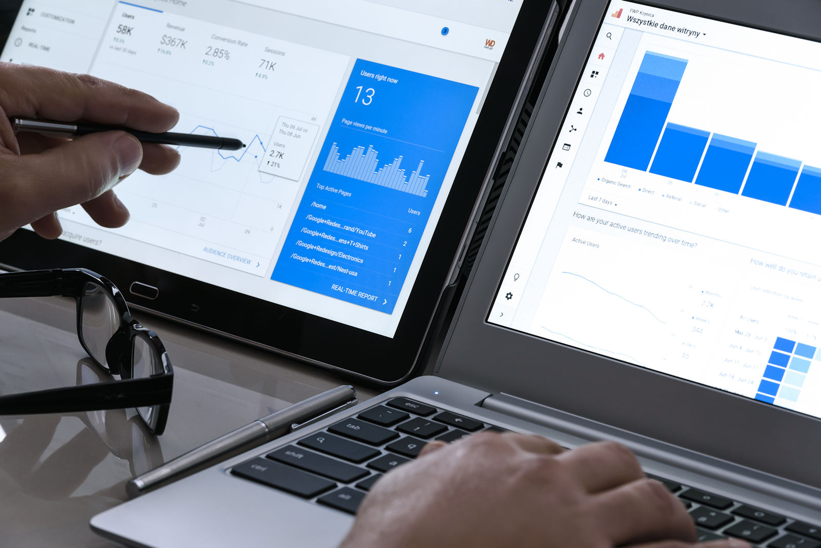 Businessman using Google Analytics in the office on the touch screen of his tablet and laptop